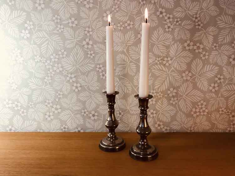 Två stycken ljusstakar i tenn med två vita brinnande kronljus